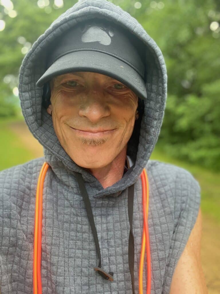 Dizzy wearing a ball cap and sleeveless hoodie with an orange Sunset Duo jump rope hanging around his neck.